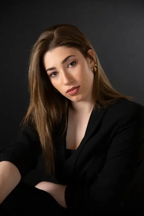 Frau mit langen braunen Haaren im schwarzen Blazer