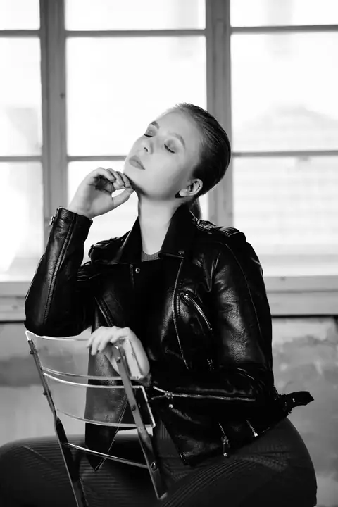 Frau in Lederjacke, die Hand am Kinn