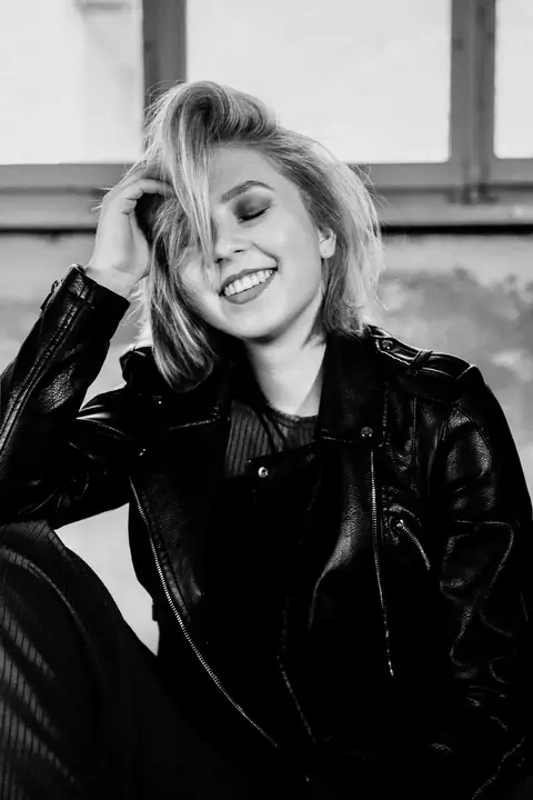 Lachende blonde Frau in Lederjacke