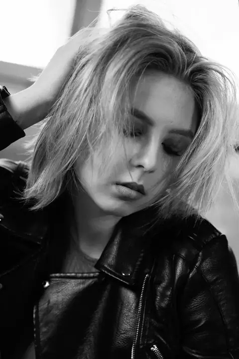 Blonde Frau mit gesenktem Blick, die Hand im Haar